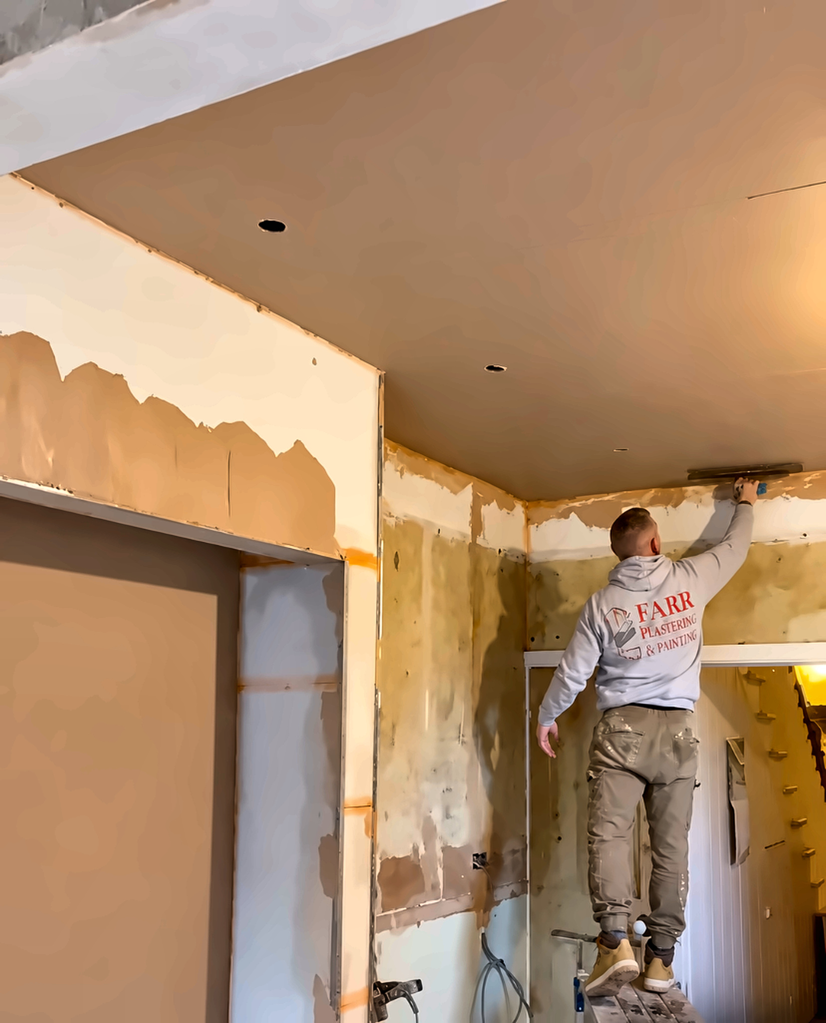 Alternate angle of a plasterer skimming a ceiling from a hop-up in SE London.