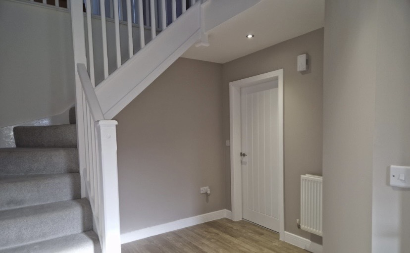 Finished plastering and decorating in a hallway with taupe walls and white staircase in Upper Norwood SE19.