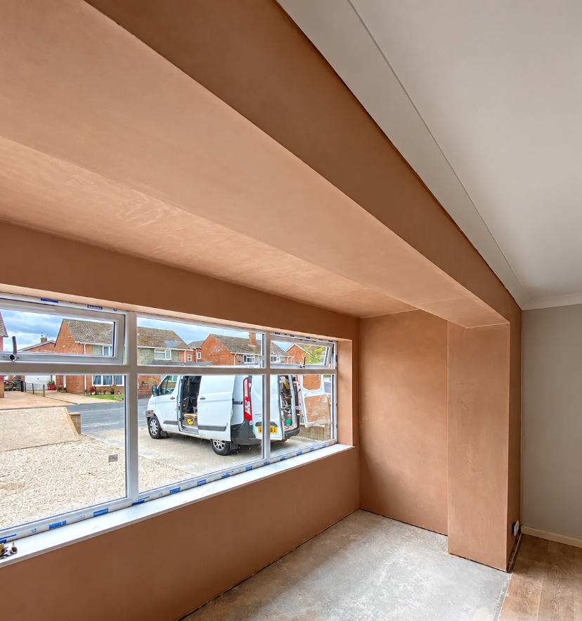 Fresh plaster skim around a bay window wall and beam, with clean corners ready for painting in SE London.